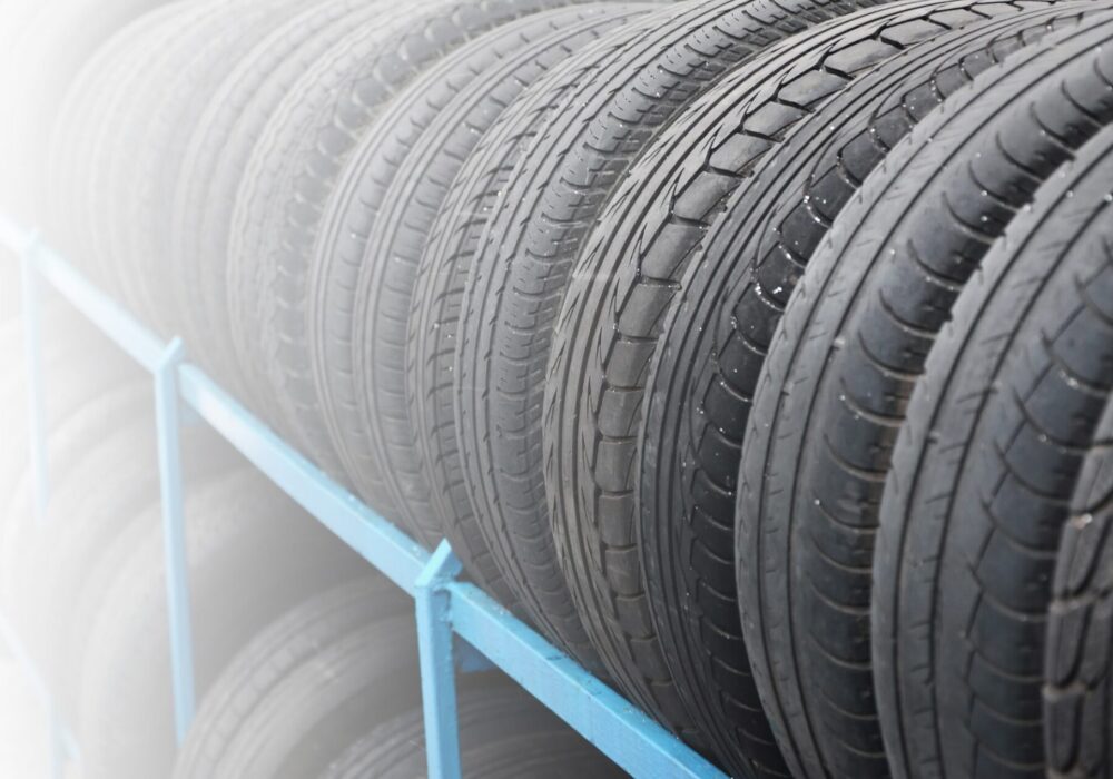 Rack with variety of car tires in automobile store. Many black tires. Tire stack background